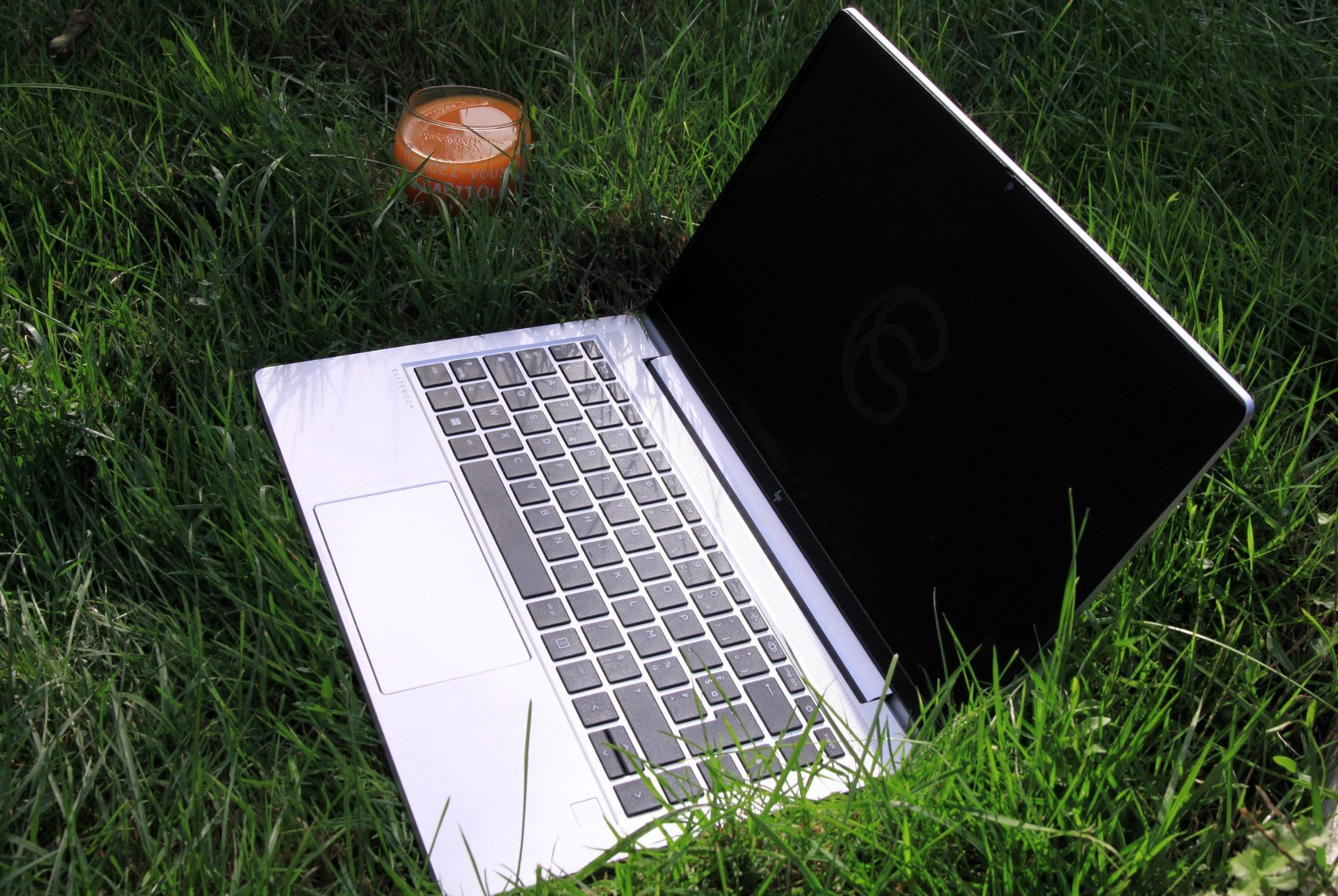 Numérique responsable Ordinateur portable ouvert sur l'herbe, écran noir, milieu naturel.